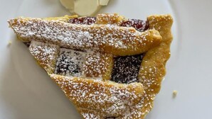 Une part de tarte saupoudrée de sucre glace, présentée sur une assiette blanche.