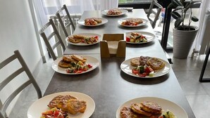 Une table à manger est dressée avec des assiettes remplies de nourriture, notamment ce qui semble être des omelettes et des salades de légumes.