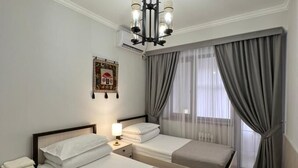 Une chambre d’hôtel avec deux lits, un lustre, une table de chevet avec une lampe et une fenêtre avec des rideaux.