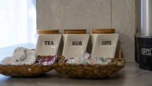 Trois récipients en céramique étiquetés « THÉ », « SUCRE » et « CAFÉ » sont posés sur un plan de travail de cuisine.