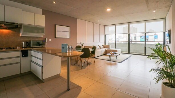 A modern kitchen with white cabinets and a dining area with a table and chairs. - w* | Picturesque 2BR with Balcony in Miraflores (Miraflores)
