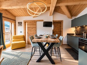 Ein stilvoller Essbereich mit Holztisch, Stühlen und einem an der Wand befestigten Fernseher.