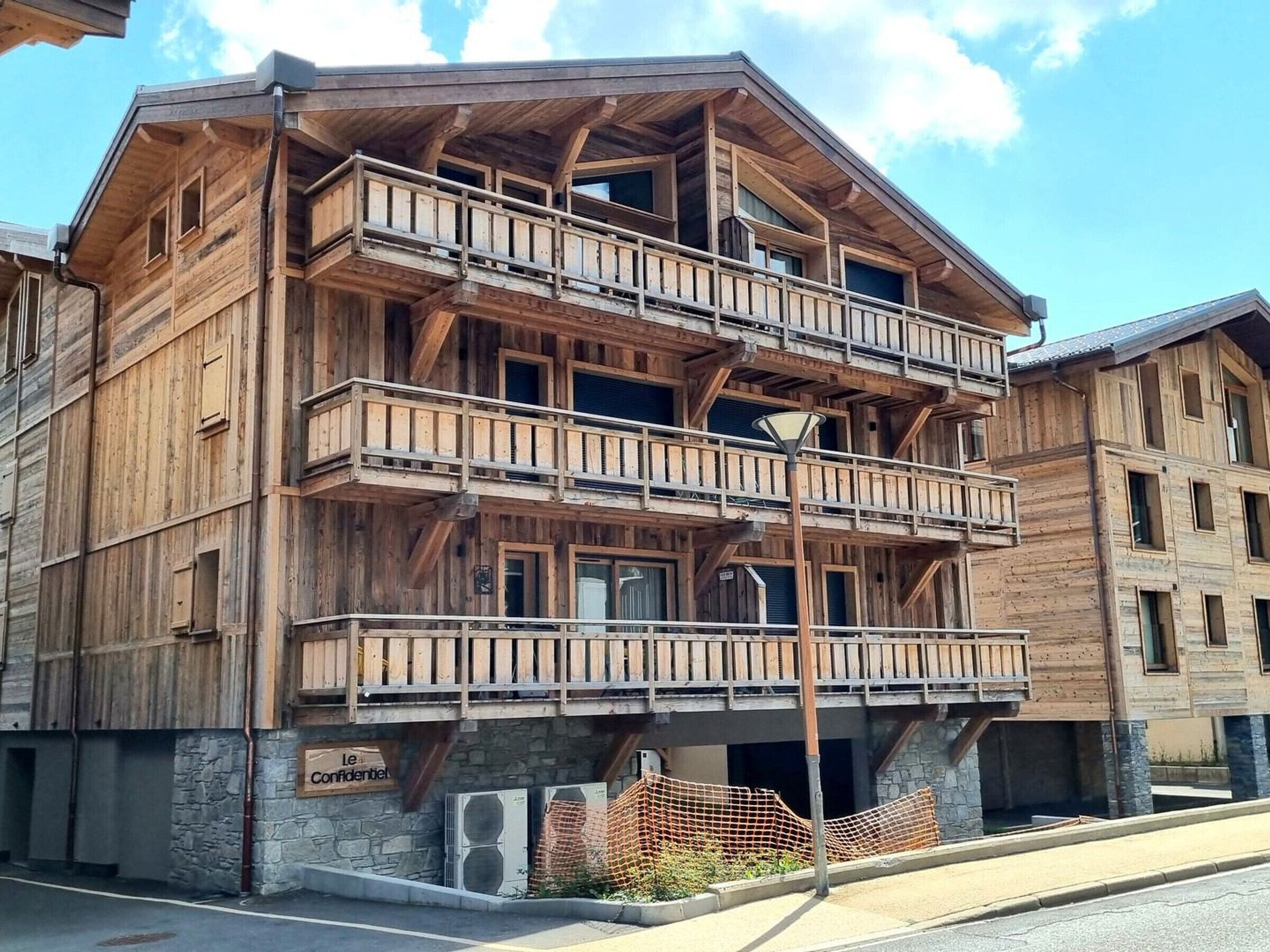 Un immeuble en bois à plusieurs étages, doté de balcons, d’une fondation en pierre et d’une enseigne sur laquelle on peut lire « Le Confidentiel ».