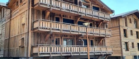 Un immeuble en bois à plusieurs étages, doté de balcons, d’une fondation en pierre et d’une enseigne sur laquelle on peut lire « Le Confidentiel ».