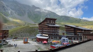 A mountainous landscape with a wooden building complex, including a restaurant and a ski lift.