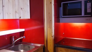 A compact kitchen with a stainless steel sink, a microwave, and wooden cabinets.