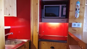 A compact kitchen with a microwave, a sink, and wooden cabinets.