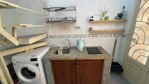 A compact kitchen with a built-in washing machine, a sink, and a small countertop. - Enjoy Homestay  (Ho Chi Minh City)