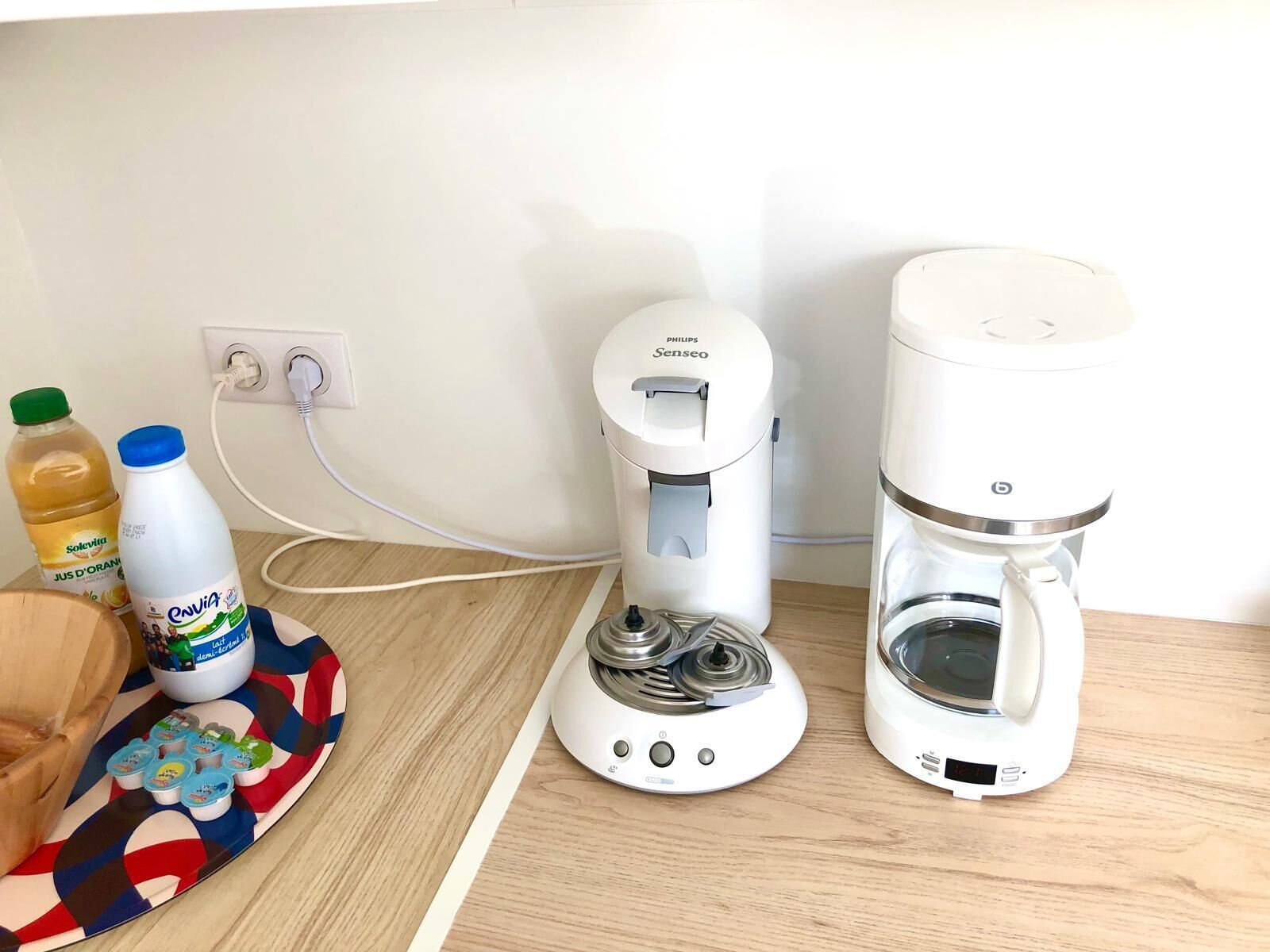 Eine Küchenarbeitsplatte mit einer Kaffeemaschine, einem Wasserspender und einem Teller mit Essensbehältern.