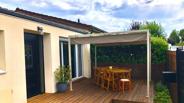 En træterrasse med overdækket patio, spisebord og stole.