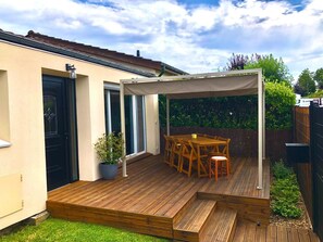 A wooden deck with a covered patio area, a dining table, and chairs. - Small family house 100m2 (Witry-lès-Reims)