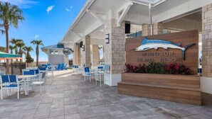 A resort with a signboard, outdoor seating, and palm trees.
