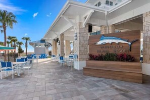 A resort with a signboard, outdoor seating, and palm trees.