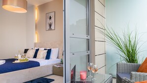 A modern bedroom with a bed, bedside table, laptop, and a glass partition. - Lumina platinium Tower Apartments (Warsaw)