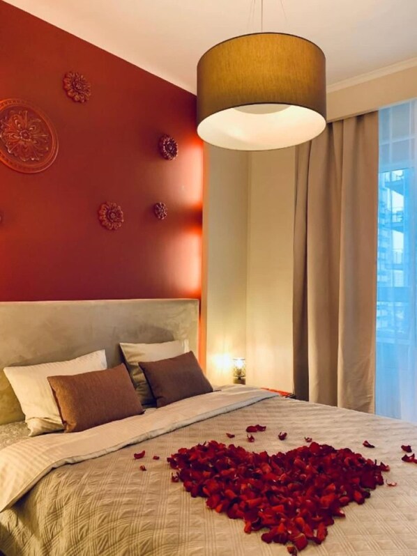 A hotel room with a large bed, a decorative wall, and a hanging light fixture.