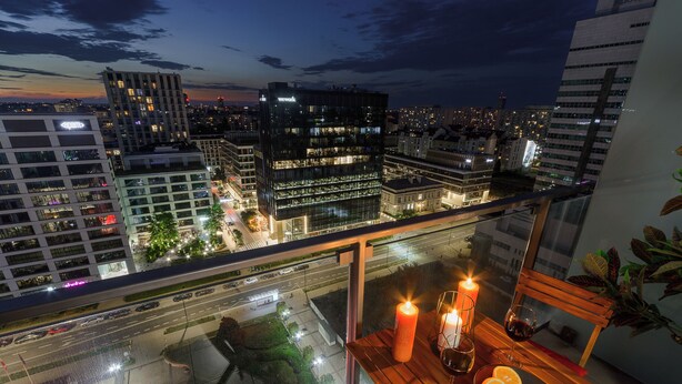A balcony with a candle, wine glass, and orange slices. - Lumina platinium Tower Apartments (Warsaw)
