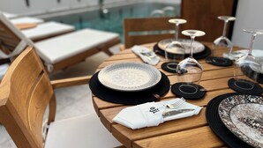 A wooden dining table set with plates, cutlery, and glasses, overlooking a pool and lounge chairs. - Oji Boutique Hotel (Alanya)