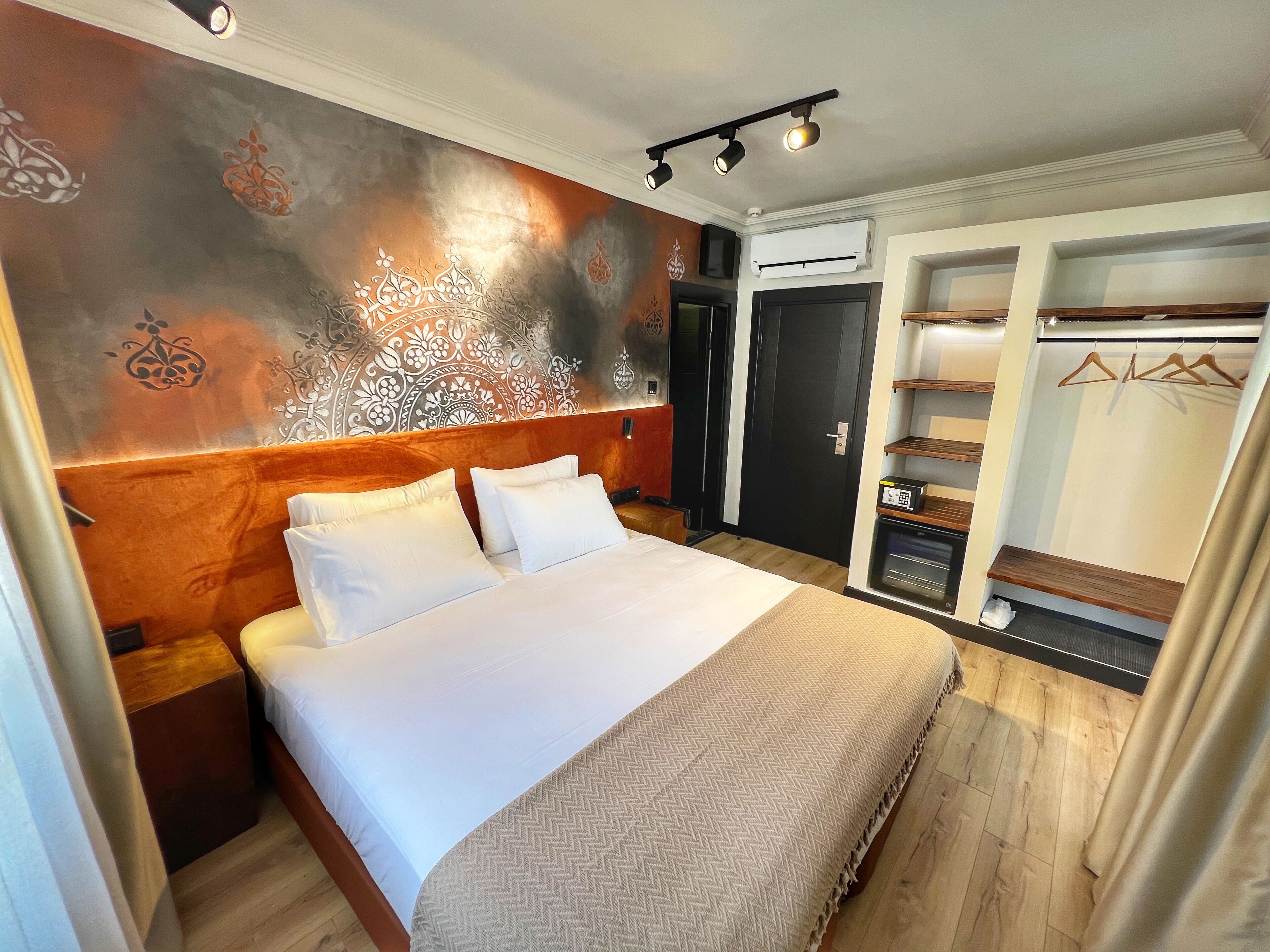 Ett hotellrum med en stor säng, en garderob med plats för att hänga kläder och en inbyggd luftkonditioneringsanläggning.
