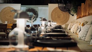 A dining area with a long table set with plates, glasses, and cutlery. There are chairs and a wooden wall in the background. - Oji Boutique Hotel (Alanya)
