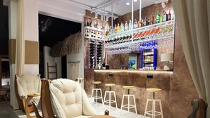 A bar area with cushioned seating, a bar counter with various bottles, and stools. - Oji Boutique Hotel (Alanya)