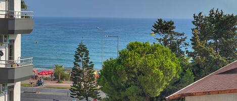 A coastal view with a building overlooking the sea, a street with a taxi, and a sign for 'Gazi Pazapa'.