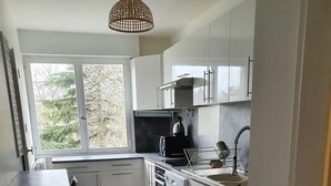 Una cocina moderna con armarios blancos, una estufa negra y un ventanal que proporciona luz natural.