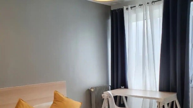 Una habitación de hotel con una cama, dos almohadas, un escritorio y una silla.