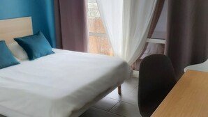 Una habitación de hotel con cama, una mesa y vistas al exterior.