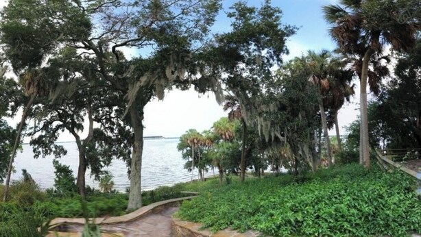A stone pathway leading to a lush garden with a view of a calm body of water. - Casa Blue - Beautiful Renovated Cottage Close to Downtown! (Safety Harbor)