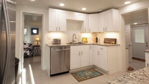 A modern kitchen with white cabinets, stainless steel appliances, and a granite countertop. - Casa Blue - Beautiful Renovated Cottage Close to Downtown! (Safety Harbor)