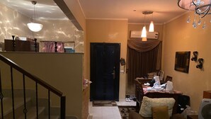 A living room with a sofa, a fan, and a staircase. - 98. Homey 2BR Townhouse | 2 Queen Beds | Garden (Sheikh Zayed City)