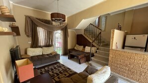 A living room with a sofa, coffee table, and TV. There is a staircase leading to another level. - 98. Homey 2BR Townhouse | 2 Queen Beds | Garden (Sheikh Zayed City)