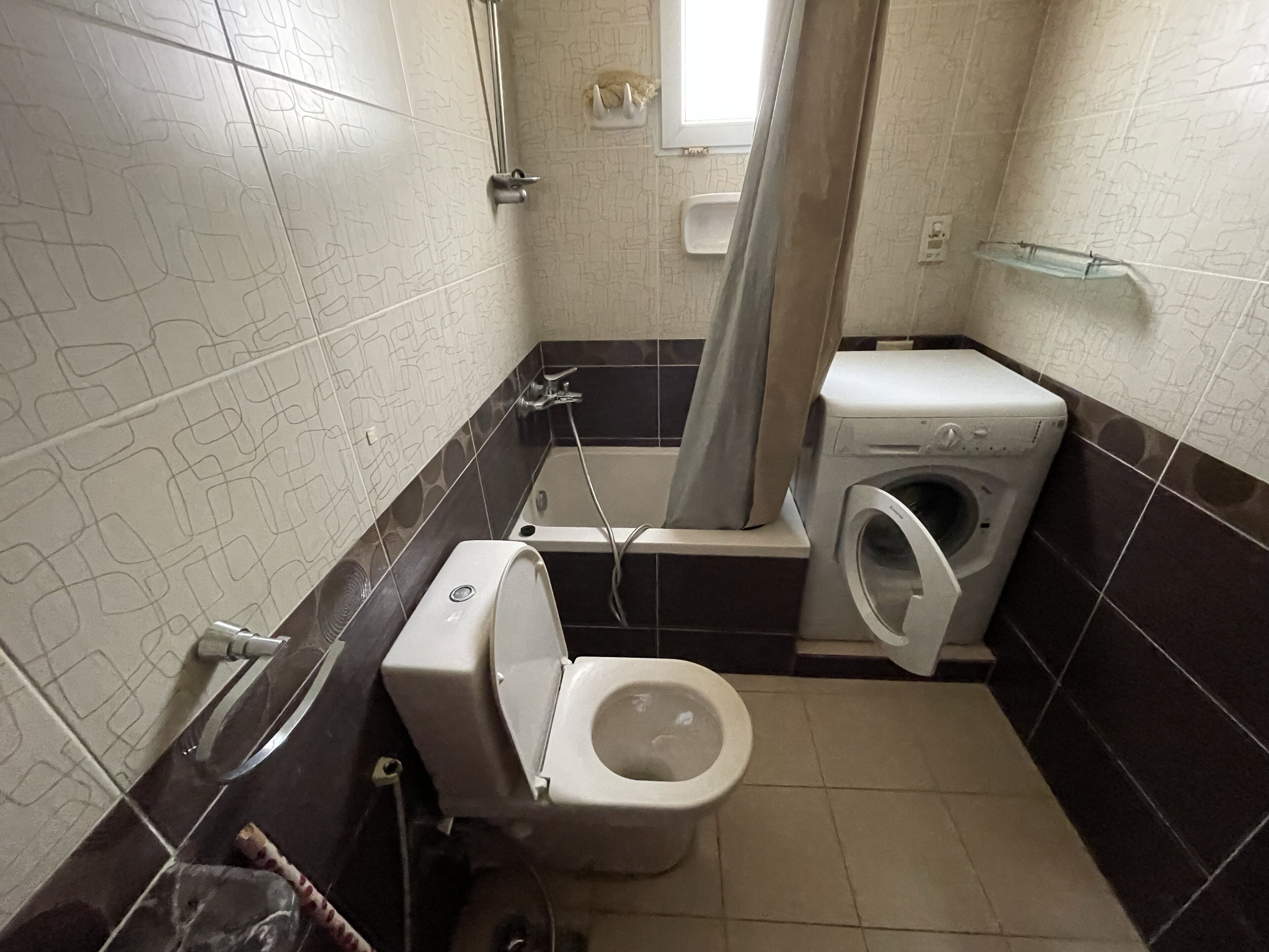 Un bany amb vàter, rentadora, dutxa i banyera.