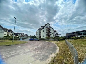 Un quartier résidentiel avec un immeuble à plusieurs étages, une route sinueuse et des voitures garées.
