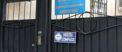A black metal gate with a sign indicating a hostel named COMPASS.
