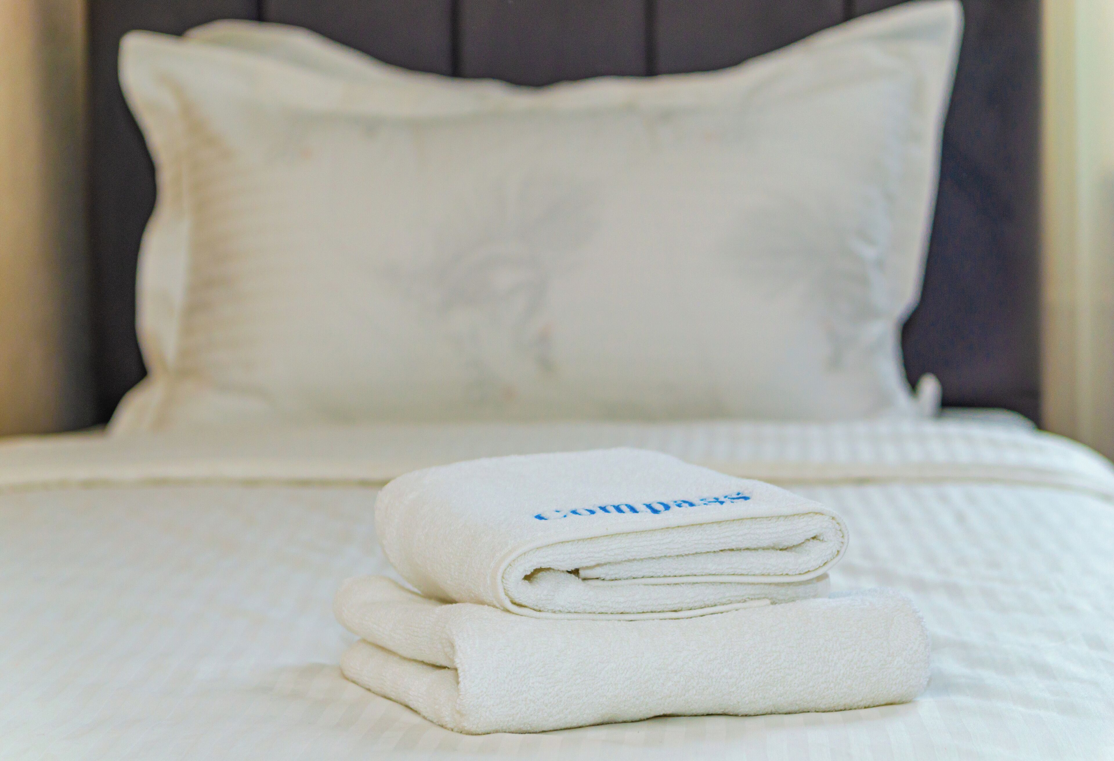 A neatly made bed with a folded white towel and a pillow.