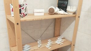 Ein Holzregal mit verschiedenen Pflegeprodukten und einem Föhn.