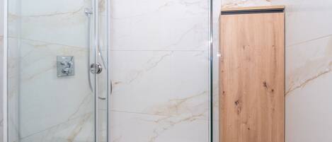 Una cabina doccia in vetro con un armadietto in legno.