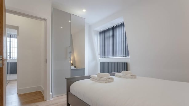 A bedroom with a bed, a large mirror, and a window with curtains. - Gorgeous Duplex Near Canary Wharf, Excel & O2 (London)