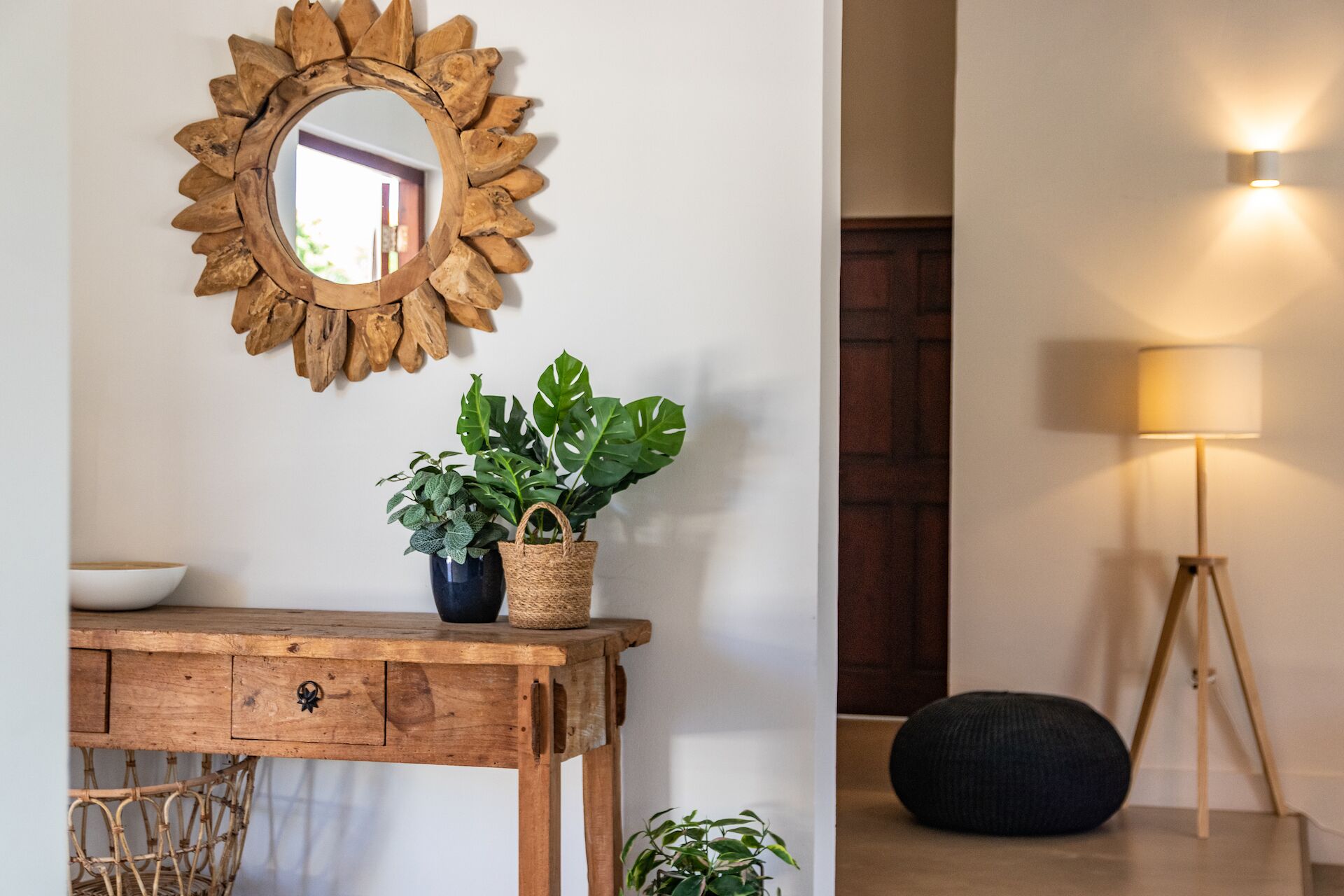 Ein Holzkonsolentisch mit Spiegel, Topfpflanzen und einer Lampe.