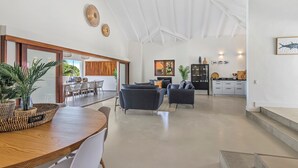 A spacious living area with a high ceiling, a dining table with chairs, a sofa, and a kitchen area with cabinets and a countertop. - Villa Blou, steps from Jan Thiel Beach (Jan Thiel)
