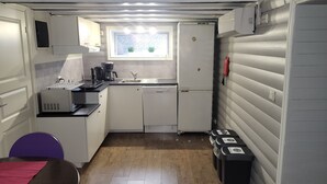 Eine kleine Küche mit Fenster, einer Kaffeemaschine und einem Kühlschrank.