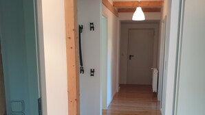 Ein Flur mit Holzboden, einer weißen Tür mit Griff und einer Decke mit freiliegenden Balken.