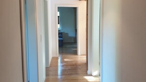 Ein Flur mit Holzboden, weißen Wänden und einer hängenden Pendelleuchte.