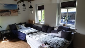 Ein Schlafzimmer mit einem großen Bett, einem Nachttisch, einem Fenster mit Jalousien und einer Wandlampe.