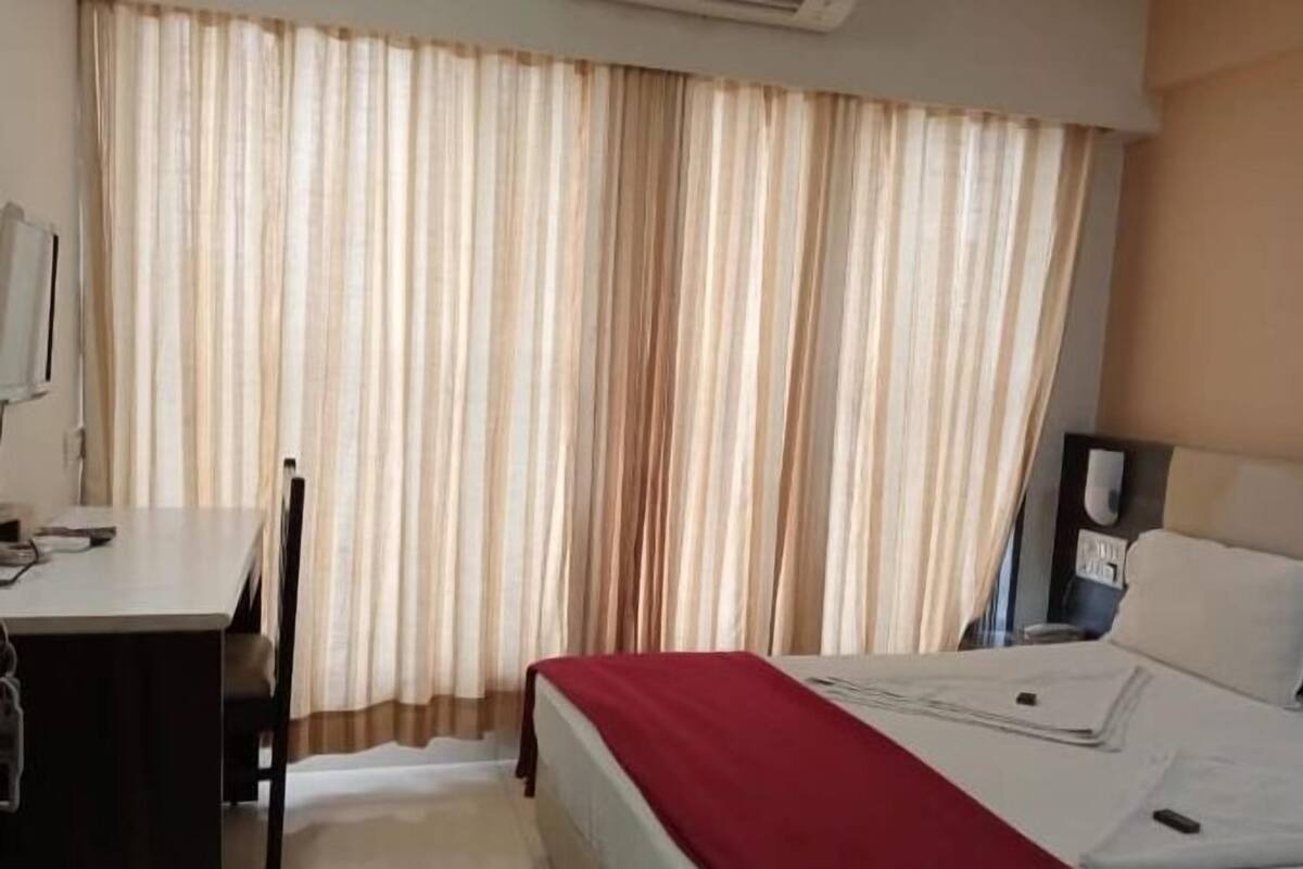 A hotel room with a bed, a desk, and a chair.