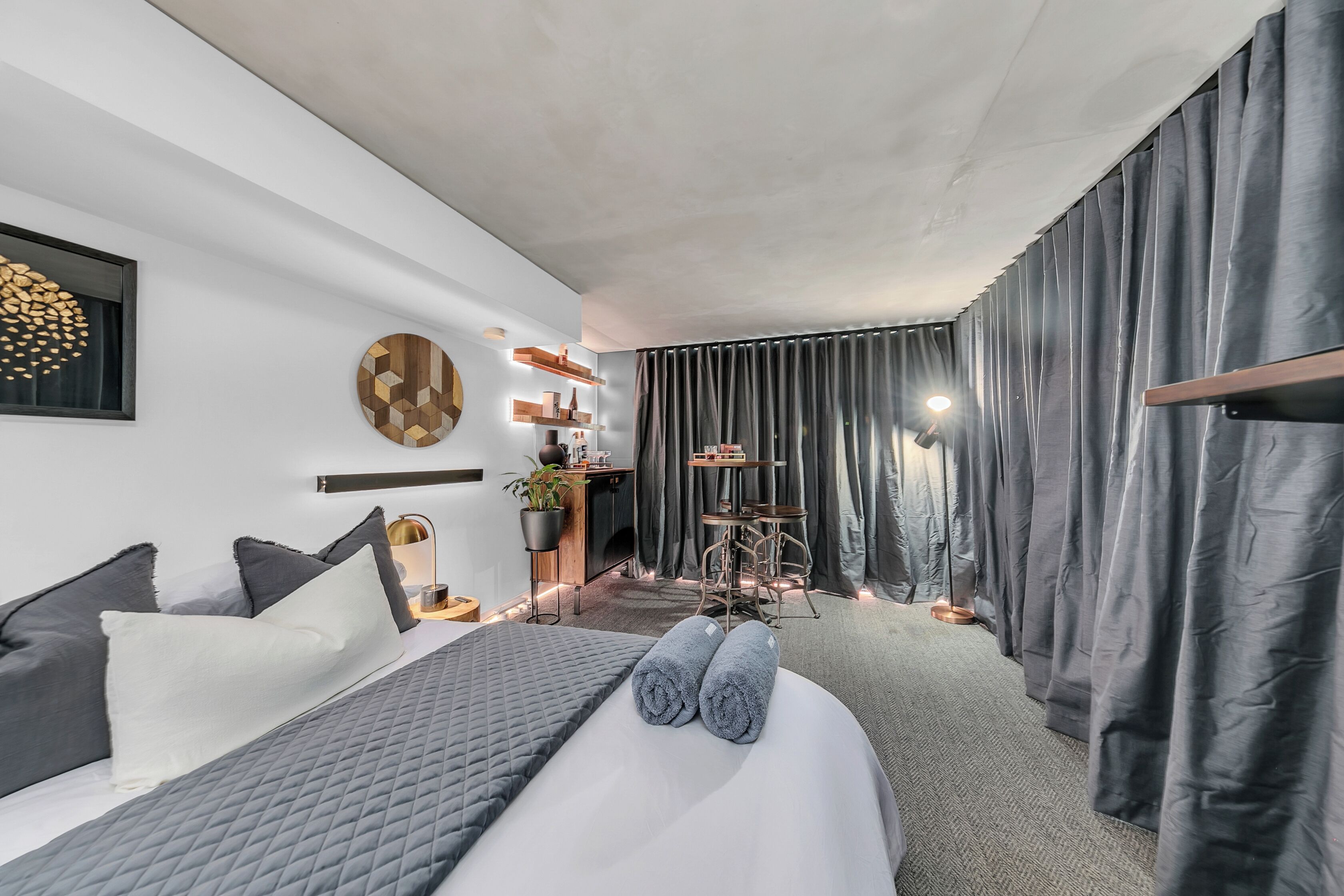 Ein modernes Hotelzimmer mit einem großen Bett, einem Schreibtisch, einem Stuhl und einem kleinen Tisch.