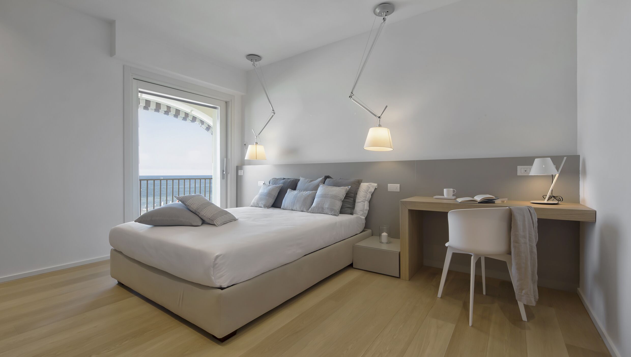 A modern bedroom with a bed, bedside tables, a desk, and a chair.