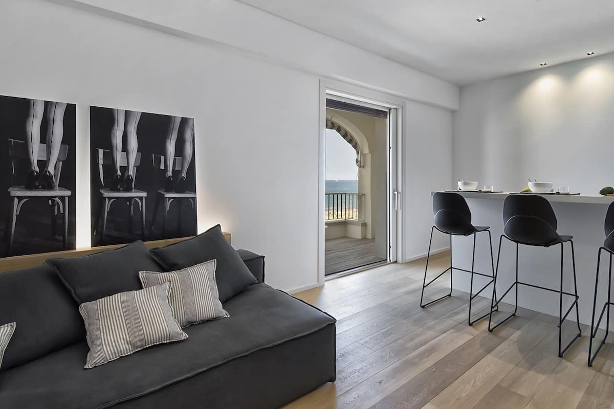 Un salon moderne avec un canapé, des œuvres d’art en noir et blanc et une vue sur l’extérieur.
