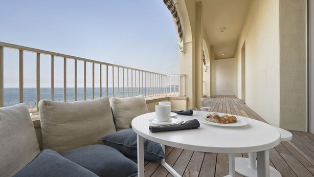 Un balcon avec une table blanche, une assiette de nourriture et une tasse.